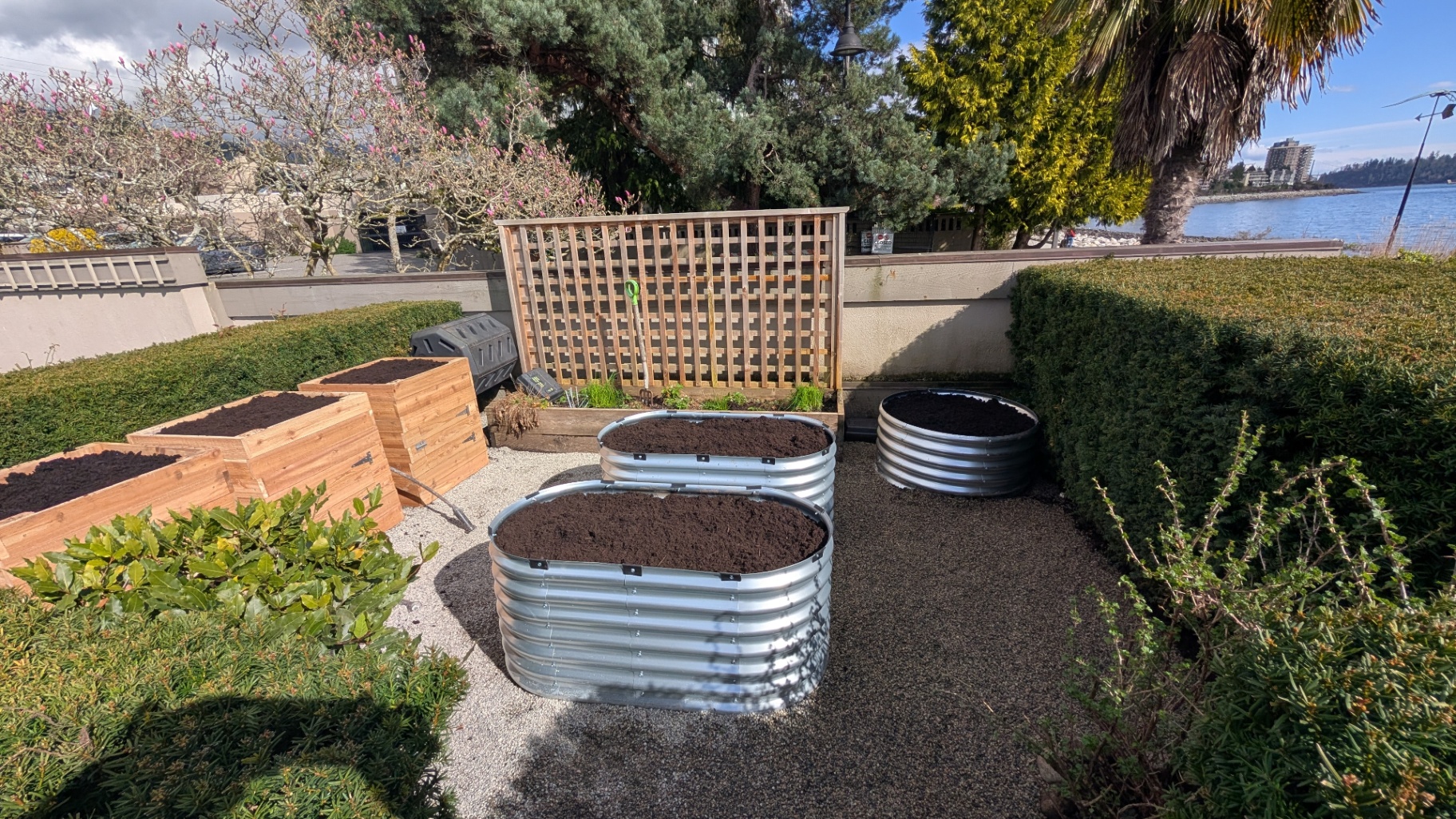 Raised garden beds in metal and cedar by the waterfront with a privacy trellis